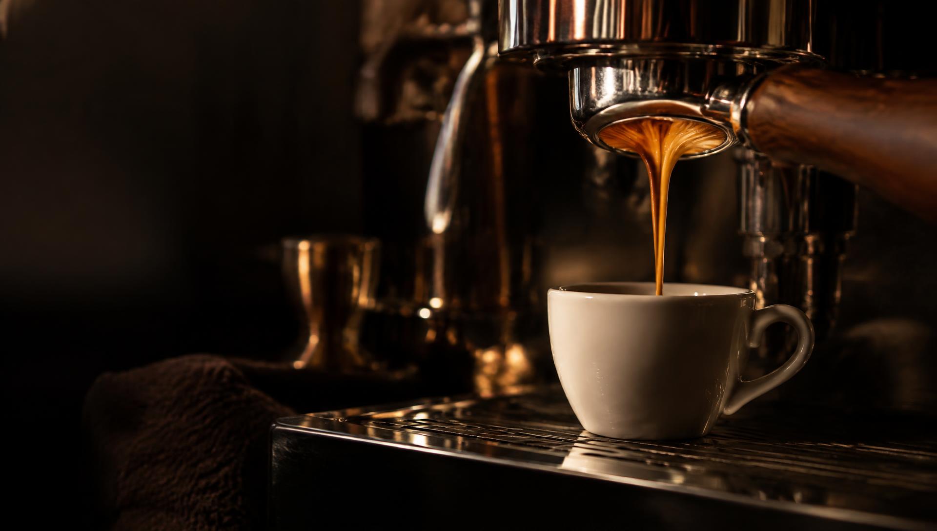 Espresso pouring from a portafilter into a porcelain cup